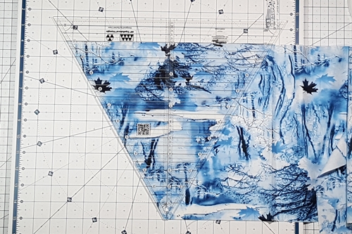 Note: rotate the ruler 180 degrees. Align the blunt tip with the bottom edge. Align the ruler's measurement line along top edge and the left side of the ruler with the angled fabric edge. Note: rotate the ruler 180 degrees. Align the blunt tip with the bottom edge. Align the ruler's measurement line along top edge and the left side of the ruler with the angled fabric edge.