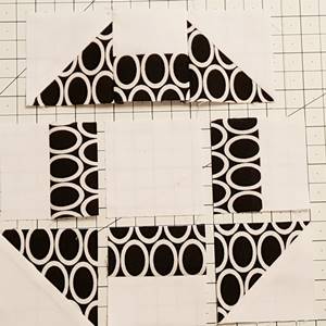 Step 5d churn dash quilt block pattern: Finger press the seam towards the bar unit. Row 1 is sewn together.