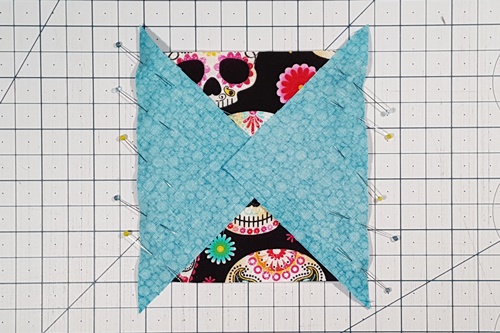 Step 5 Economy Quilt Block: Right sides together, align creased side of each triangle along vertical sides of center square, nesting creases made in the previous step. Pin if desired. Step 5 Economy Quilt Block: Right sides together, align creased side of each triangle along vertical sides of center square, nesting creases made in the previous step. Pin if desired.