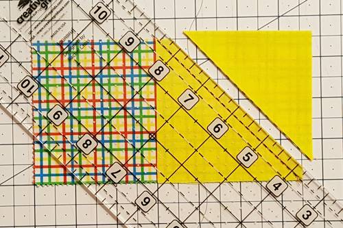 Step 4 Place the quarter inch line of a quilting ruler on the stitched line and use a rotary cutter to cut along the edge of the ruler, leaving a 1/4 inch seam on the flying geese unit.