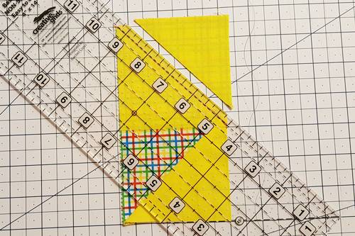 Step 7 Place the quarter inch line of a quilting ruler on the stitched line and use a rotary cutter to cut along the edge of the ruler, leaving a 1/4 inch seam on the flying geese unit.