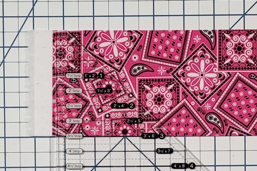 How to Make Flying Geese Step 2: align half square triangle ruler measurement line that is the width of the fabric strip along the bottom of the fabric strip.
