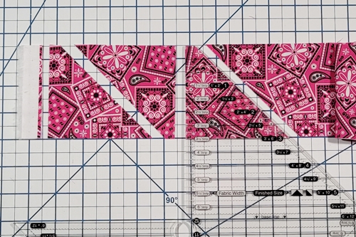 How to Make Flying Geese Step 6: rotate the ruler as in Step 4 aligning the straight side of the ruler with the straight edge of the fabric strip. Make a cut along the angled edge of the ruler.