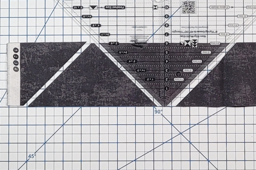 How to Make Flying Geese Step 10: rotate the ruler 180 degrees. Align the ruler's
measurement line with the top of the fabric strip and the blunt tip with the bottom of the strip.