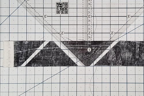 Step 2 How To Use A Quarter Square Triangle Ruler: Rotate ruler 180 degrees, align tip on bottom of strip, align left edge of ruler with previous cut. Cut along right side of ruler. Step 2 How To Use A Quarter Square Triangle Ruler: Rotate ruler 180 degrees, align tip on bottom of strip, align left edge of ruler with previous cut. Cut along right side of ruler.