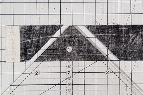 Step 1 How To Use A Quarter Square Triangle Ruler: Place measurement line of  ruler on bottom edge of strip, place left side of ruler to right of selvage edge, cut strip along right and left of ruler. Step 1 How To Use A Quarter Square Triangle Ruler: Place measurement line of  ruler on bottom edge of strip, place left side of ruler to right of selvage edge, cut strip along right and left of ruler.