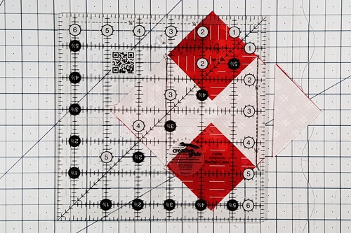 Step 4b Square in a Square: Place 1/4 inch measurement line of a quilting ruler along the seam line of one small triangle. Cut along the ruler's edge. Rotate the unit. Repeat to cut opposite corner. Step 4b Square in a Square: Place 1/4 inch measurement line of a quilting ruler along the seam line of one small triangle. Cut along the ruler's edge. Rotate the unit. Repeat to cut opposite corner.