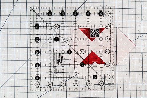 Step 5b Square in a Square: Place 1/4 inch measurement line of ruler on seam line of one small triangle. Cut along the ruler's edge. Rotate unit and repeat to cut opposite corner. Step 5b Square in a Square: Place 1/4 inch measurement line of ruler on seam line of one small triangle. Cut along the ruler's edge. Rotate unit and repeat to cut opposite corner.