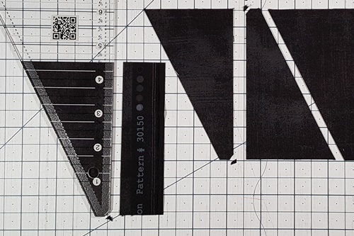 Step 9 Triangle in a Square: rotate fabric 180 degrees so uncut side is on right. Rotate ruler 180 degrees with tip at bottom of strip and measurement line at top of strip. Make a cut. Step 9 Triangle in a Square: rotate fabric 180 degrees so uncut side is on right. Rotate ruler 180 degrees with tip at bottom of strip and measurement line at top of strip. Make a cut.